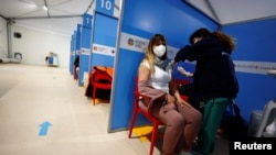 Seorang petugas kesehatan menyuntikkan vaksin COVID-19 buatan AstraZeneca kepada seorang pelawat di Bandra Fiumicino di Roma, Italia, 8 Maret 2021.