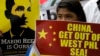 FILE - Protesters display a Philippine flag and placards while shouting slogans as they march towards the Chinese Consulate at the financial district of Makati city east of Manila.