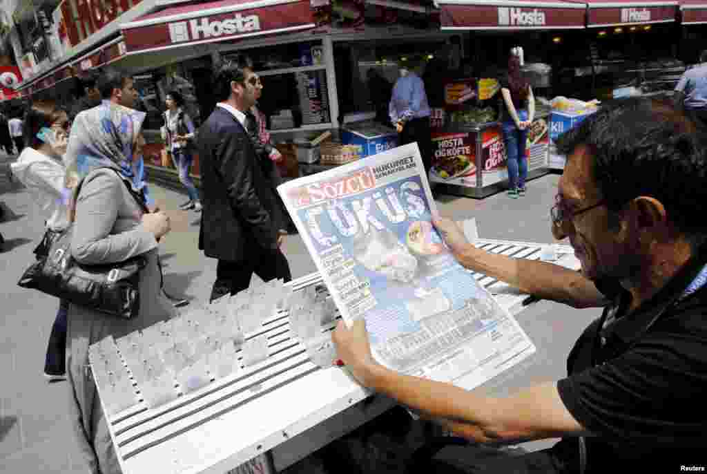 A lottery ticket vendor reads a Turkish newspaper published with an headline reads "downfall" and a portrait of Turkey's President Tayyip Erdogan in Ankara, June 8, 2015.
