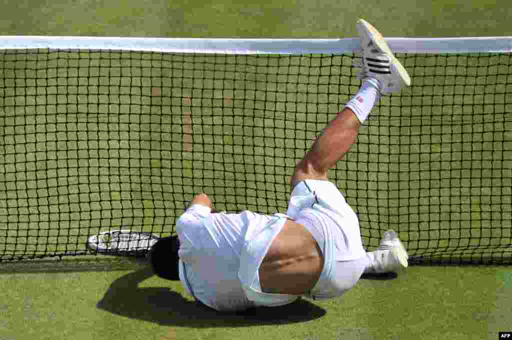 Serbia's Novak Djokovic falls into the net during the men's singles quarter-final match against Croatia's Marin Cilic on day nine of the 2014 Wimbledon Championships at the All England Tennis Club in Wimbledon, southwest London.