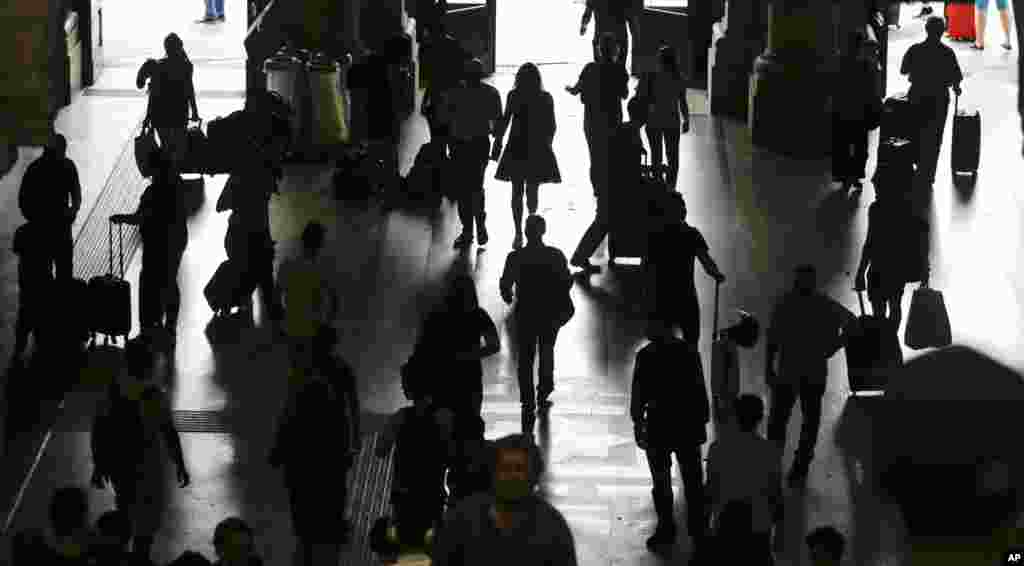 People are silhouetted as they walk in a railway station, in Milan, Italy, during a general transportation strike. Travelers faced train and flight cancellations, commuters crowded the streets in private cars, due to the strike against privatization of the transportation sector. 