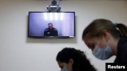 FILE - Kremlin critic Alexey Navalny is seen on a screen via videolink during a hearing to consider his lawsuits against the penal colony where he is being held, over detention conditions there, at the Petushki District Court, in Petushki, Russia, May 26, 2021.