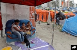 In this Monday, Dec. 11, 2017 photo, a mother feeds lunch to her children in the squatter community coined "Povo Sem Medo," or Fearless People meet to discuss their future in Sao Bernardo do Campo, a suburb of Sao Paulo, Brazil.