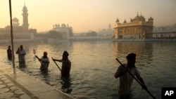 FILE- In this Nov. 17, 2013, file photo, Indian Sikh devotees clean the tank early in the morning at the Golden Temple, on the birth anniversary of Guru Nanak, the first Sikh Guru in Amritsar, India. The chronic air pollution is now threatening the holiest shrine in the Sikh religion, making the once-gleaming walls of the Golden Temple dingy and dull.