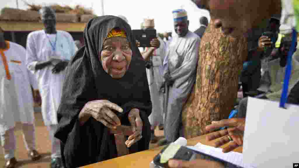 Une vieille femme nigériane fait valider sa carte de vote à travers un lecteur d'empreintes digitales, avant de revenir voter plus tard dans la journée, dans la ville natale du candidat de l'opposition le général Muhammadu Buhari, en Daura, Nigeria samedi 28 mars 2015.