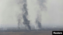 De la fumée s'échappe à Bartila, à l'est de Mossoul lors des combats contre le groupe État islamique, Irak, le 18 octobre 2016. 