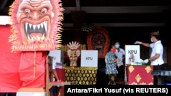 Seorang perempuan mengenakan masker saat memberikan suara di sebuah TPS di Badung, Provinsi Bali, 9 Desember 2020 di tengah pandemi Covid-19. (Foto: Antara/Fikri Yusuf via REUTERS)