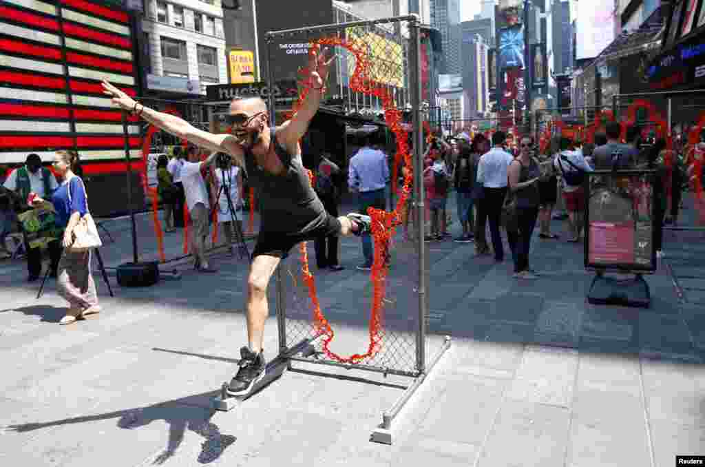 A man leaps through one of a series of 17 sculptures made of copper and steel panels cut out with various sizes of human silhouettes by Cuban-born artist Arles del Rio in New York's Times Square.