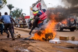 A man carries a poster of Ugandan musician turned politician Robert Kyagulanyi, also known as Bobi Wine, while protesting the arrest of Kyagulanyi during his presidential rally in Kampala, Uganda, Nov. 18, 2020.
