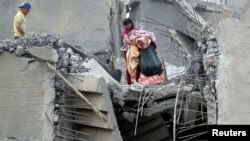 FILE - A Palestinian holds his belongings from the rubble of his house that was destroyed by an Israeli air strike, Gaza City May 7, 2019. 