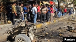 Residents are seen inspecting the site of a car bomb attack in the Karrada district in Baghdad February 17, 2013.