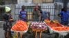 une femme achète des tomates et des oignons à des marchands ambulants à Lagos, au Nigéria, le 13 avril 2020. Le confinement dû à la lutte contre le covid-19 limite la circulation des personnes, rendant difficile l'approvisionnement. (Photo AP / Sunday Alamba)
