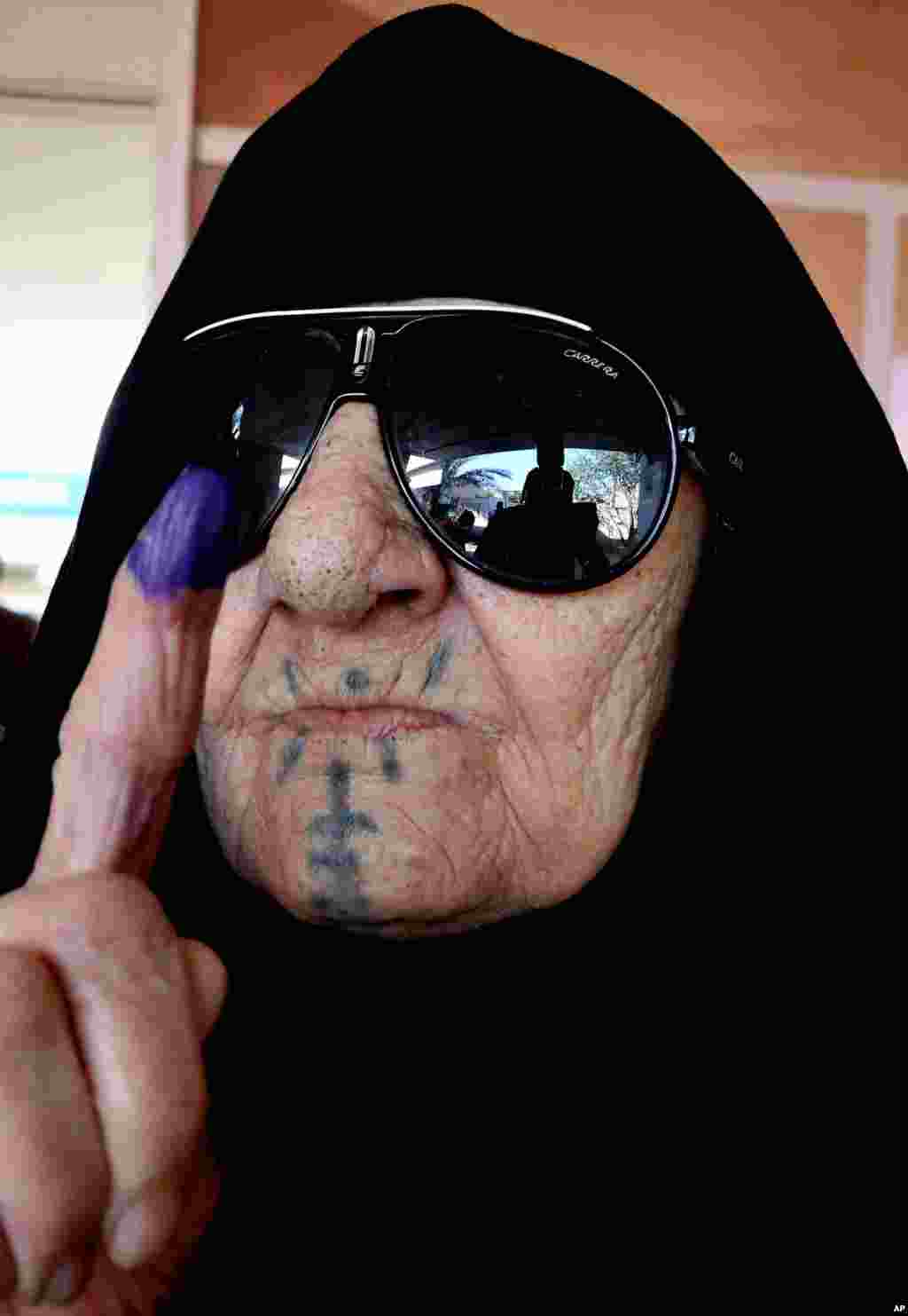 An elderly Iraqi woman shows her ink-stained finger after casting her vote, Baghdad, April 30, 2014. 