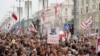 FILE - Belarusian opposition supporters carry old Belarusian flags and a poster with a portrait of Belarusian President Alexander Lukashenko reading "Go away," at a rally at Independence Square in Minsk, Belarus, Aug. 23, 2020. 