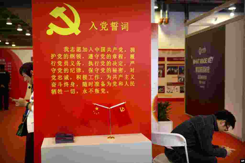 2018年9月26日,在北京的中国改革开放40周年展览会上,参观者使用智能手机。展品中有中共入党誓词。中共9000万党员中,有多少人真正相信这些誓词?