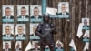 A Ugandan riot policeman blocks the gate of the party headquarters of opposition leader Kizza Besigye, shortly after raiding the premises for the second time in a week, in the capital Kampala, Uganda, Feb. 22, 2016. 