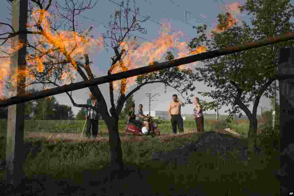 Warga lokal melihat kobaran api dari pipa gas yang rusak terkena bom mortir dalam pertempuran antara pasukan pemerintah Ukraina dan militan pro-Rusia di luar kota Slovyansk, Ukraina timur, (19/5). (AP/Alexander Zemlianichenko)