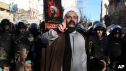 Surrounded by policemen, a Muslim cleric addresses a crowd during a demonstration to protest the execution of Saudi Shiite Sheikh Nimr al-Nimr, in front of the Saudi embassy in Tehran, Iran, Jan. 3, 2016.