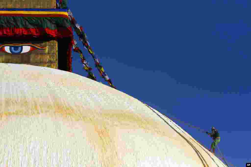 Seorang pria Nepal memanjat stupa 'Boudhanath' di Katmandu, yang termasuk warisan dunia dan sedang menjalani renovasi.