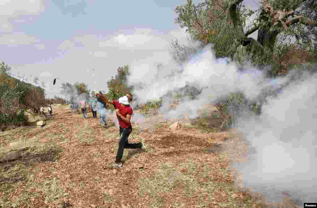 Seorang demonstran Palestina melemparkan kembali kaleng gas air mata yang ditembakkan oleh tentara Israel dalam bentrokan mengenai ketegangan di masjid al-Aqsa di Yerusalem, di desa Budrus dekat Ramallah, Tepi Barat (2/10). (Reuters/Mohamad Torokman)