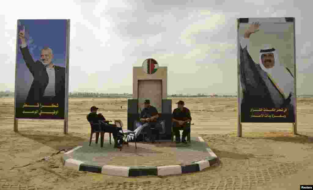 Members of Hamas security forces sit between posters depicting senior Hamas leader Ismail Haniyeh (L) and Qatar's Emir Sheik Hamad bin Khalifa al-Thani (R) in Khan Younis in the southern Gaza Strip October 22, 2012.