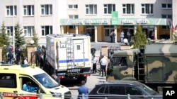 Ambulensi na malori yaliyoegeshwa kwenye lango la shule ambako shambulizi lilioua wanafunzi wasiopungua saba lilitokea nchini Russia tarehe 11, Mei, 2021. 