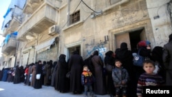 FILE - Women and children queue to receive free meals in Aleppo, Syria, Feb. 2, 2017. 