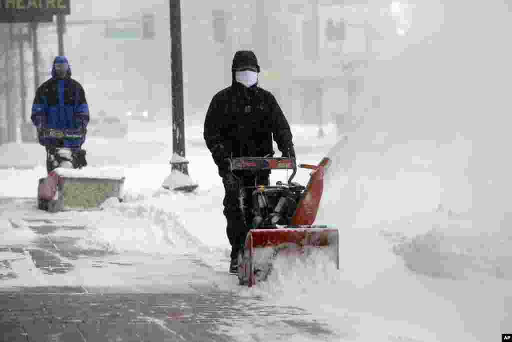 Para pekerja mencoba membersihkan salju dari trotoar dalam badai salju di Boston (27/1). (AP/Steven Senne)