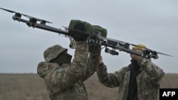 Para pilot sedang membawa drone di tempat latihan di wilayah Kyiv pada 23 Februari 2024, di tengah invasi Rusia ke Ukraina. (Foto: AFP)