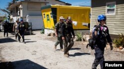 Para petugas dari Badan Managemen Darurat dan petugas kepolisian Lee County menyisir wilayah taman karavan di wilayah Fort Myers Beach, Florida, pada 3 Oktober 2022, setelah badai Ian menerjang wilayah tersebut. (Foto: Reuters/Marco Bello)