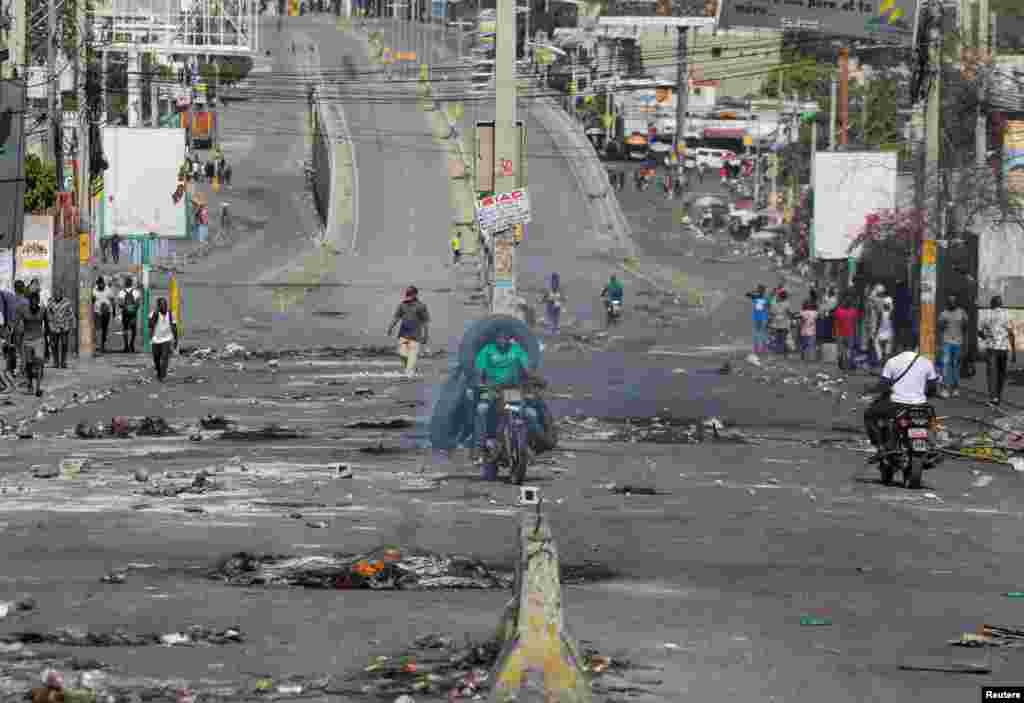 People pass through an empty street with remains of barricades during a nationwide strike against rising fuel prices, in Port-au-Prince, Haiti, Sept. 26, 2022. 