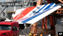 FILE - Workers unload debris, belonging to the crashed Air France flight AF447, from the Brazilian Navy's Constitution Frigate in the port of Recife, northeast of Brazil, June 14, 2009. 
