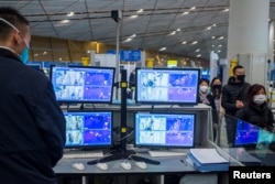 北京国际机场的工作人员正在使用热扫描仪查看抵达乘客的体温。（2020年1月25日）