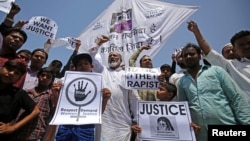 FILE - People hold placards at a rally condemning the rapes of two girls, aged 8 and 11, in Ahmedabad, India, April 22, 2018.