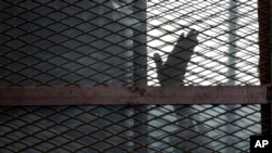 Un accusé gesticule dans la cage des accusés lors de son procès devant un tribunal du Caire, en Égypte, le 22 août 2015.