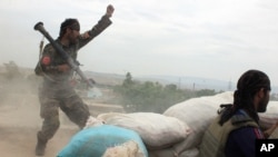 FILE - An Afghan National Army soldier, left, shouts against the Taliban, after firing a rocket towards Taliban positions, on the outskirts of Kunduz, northern Afghanistan, April 16, 2016.