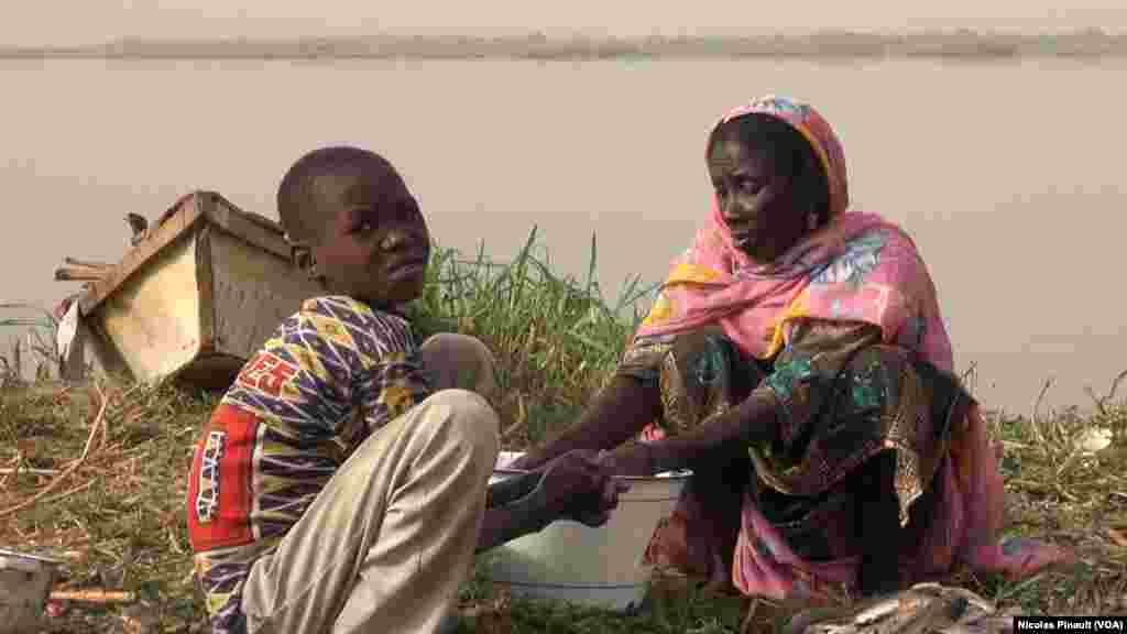 Une mère et son fils nettoient les poissons dans le village de Tagal, Tchad, le 24 avril 2017 (VOA/Nicolas Pinault)