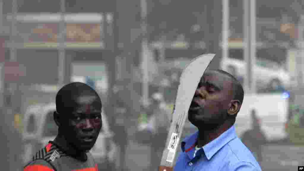 Un immigrant armé d'une machette, aperçu sur une rue au cours d'affrontements avec la police et des xénophobes qui ont attaqué les propriétaires de magasins étrangers dans le centre-ville à Durban, Afrique du Sud, mardi 14 Avril 2015.