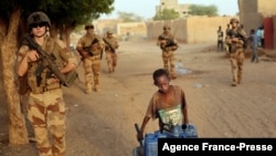 French soldiers patrolling the streets of Gao, Mali, walk past a boy carrying canisters on Dec. 4, 2021.