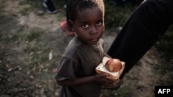 Lokacin da wani yaro ya karbo abinci a wani sansani a Mozambique, ranar 27 ga watan Maris, 2019.
