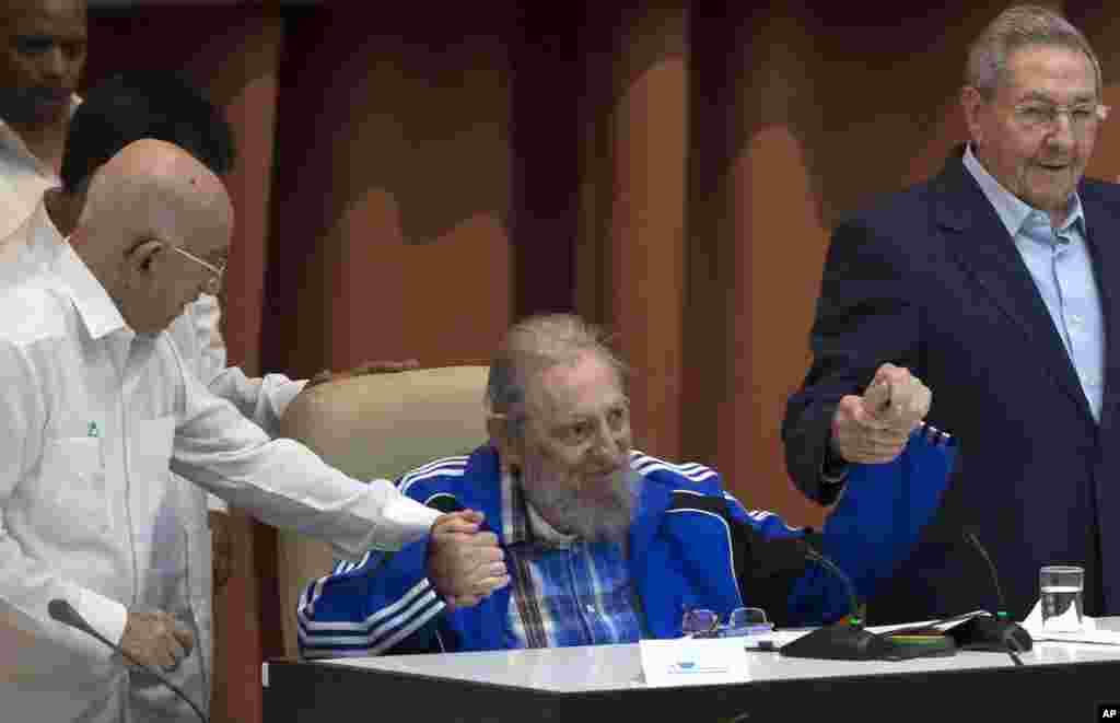 Fidel Castro assis tient la main de son frère, le président cubain Raúl Castro, à droite, et du deuxième secrétaire du Comité central, José Ramón Machado Ventura, quelques instants avant le chant de l'hymne du Parti communiste lors des cérémonies de clôture du 7e Congrès de la Parti communiste cubain, à La Havane, Cuba, le mardi 19 avril 2016.