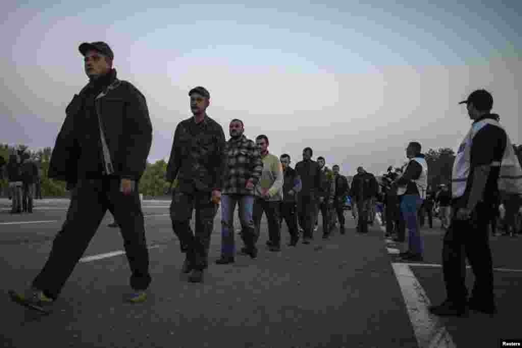 Ukrainian government soldiers, who were taken prisoners-of-war, walk along a road to be exchanged, north of Donetsk, eastern Ukraine, Sept. 28, 2014.