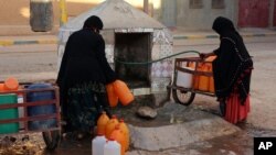 Des femmes marocaines remplissent des conteneurs avec de l'eau d'un tuyau, à Zagora, au sud-est du Maroc le 19 octobre 2017.