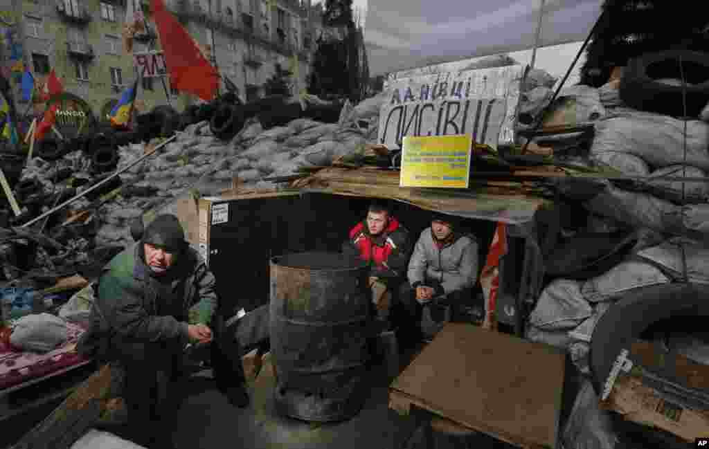 Pro-European Union activists warm themselves sitting in their shelter inside a barricade during a rally in Independence Square, Kyiv, Dec. 18, 2013.