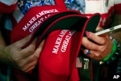 FILE - In this June 2, 2016, file photo, a woman holds hats to get them autographed by Republican presidential candidate Donald Trump during a rally in San Jose, Calif. (AP Photo/Jae C. Hong, File)