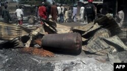 Les policiers assurent la sécurité devant les restes des maisons et des commerces incendiés dans le village de Konduga, dans le nord du Nigeria, 12 février 2014.