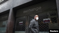 Un hombre usando una mascarilla pasa frente a un casa de cambio cerrada debido a la cuarentena, en el centro de Buenos Aires el 22 de mayo de 2020.