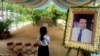 FILE - A girl stands by a portrait of Kem Ley, a Cambodian prominent political analyst, at his grave in Ang Takok, Cambodia, Nov. 20, 2016.