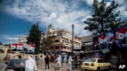 Pekerja menyemprotkan desinfektan untuk mencegah penyebaran virus corona di Qamishli, Suriah, 24 Maret 2020. (Foto: AP)