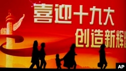 北京居民走过迎接中共十九大召开的大型电子屏幕。（2017年10月15日）